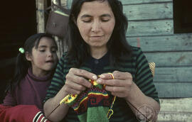 Mujer tejiendo junto a niña