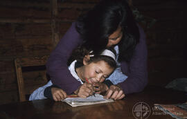 Mujer junto a niña, escribiendo en un cuaderno