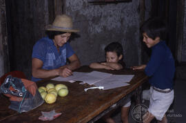 Mujer junto a dos niños escribiendo sobre una mesa