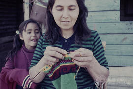 Mujer tejiendo junto a niña