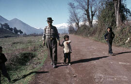 Hombre en camino rural caminando junto a un niño