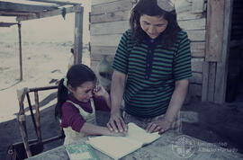 Mujer junto a una niña viendo un cuaderno