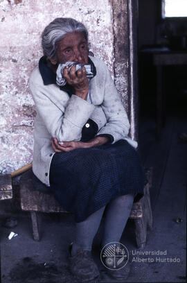 Anciana sentada afuera de una casa